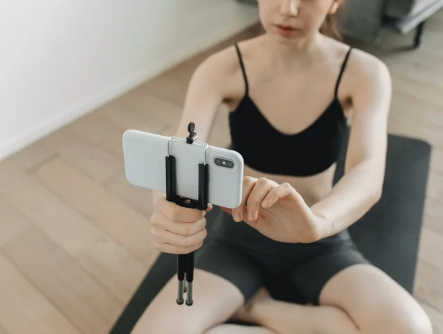 A woman using a smartphone on a tripod to film her yoga session indoors. Five official records to check before testing fitness content demand, with a test for each