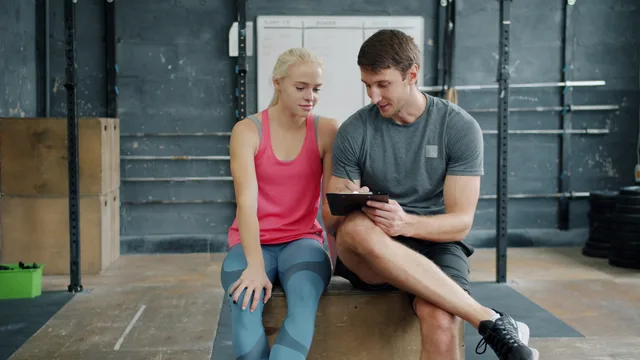 A personal trainer discusses workout plans with a client at a gym. How fitness creator suppliers get reviewed here, and why hold is a legitimate verdict